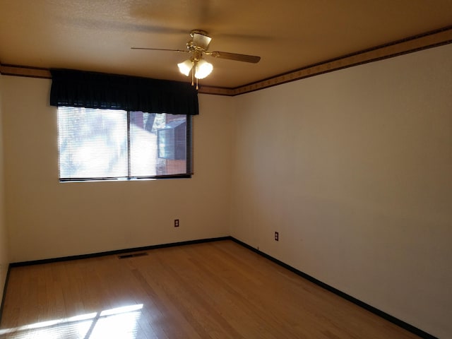 unfurnished room with light wood-type flooring, visible vents, ceiling fan, and baseboards