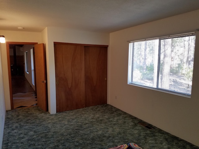 unfurnished bedroom featuring a closet, visible vents, and dark carpet