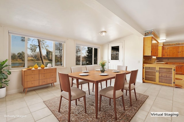 dining room featuring light tile patterned floors and lofted ceiling with beams