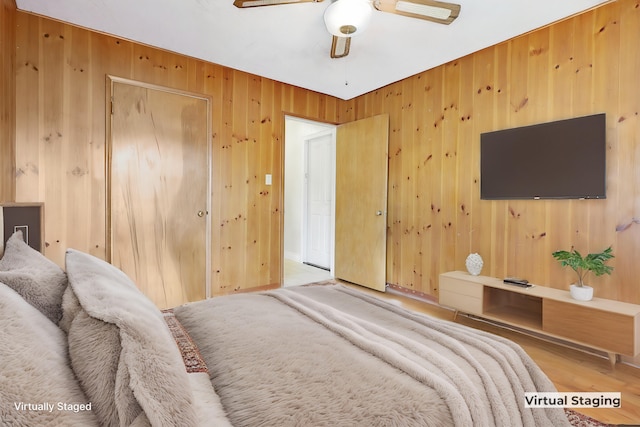 bedroom with ceiling fan, hardwood / wood-style floors, and wood walls