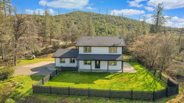 view of front facade with a mountain view, a front lawn, and a patio