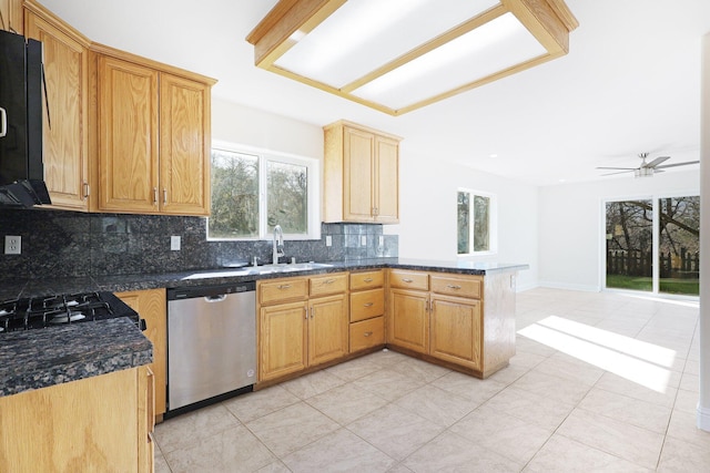 kitchen featuring sink, decorative backsplash, dark stone counters, stainless steel dishwasher, and kitchen peninsula