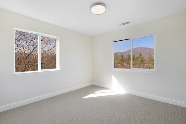 spare room featuring a mountain view and carpet