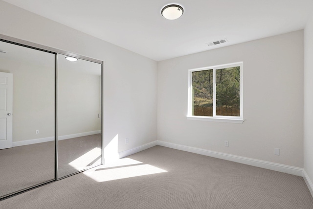 unfurnished bedroom with light colored carpet and a closet