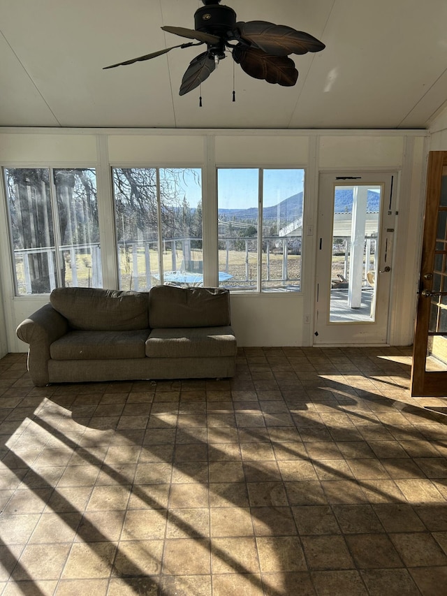 sunroom with ceiling fan and a mountain view