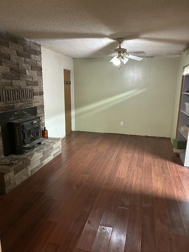 unfurnished living room featuring hardwood / wood-style floors, ceiling fan, a textured ceiling, and a wood stove