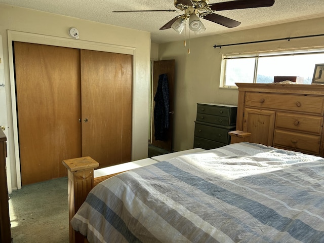 bedroom featuring ceiling fan, light carpet, a closet, and a textured ceiling