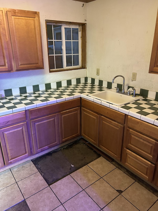 kitchen with tile counters, sink, and light tile patterned floors