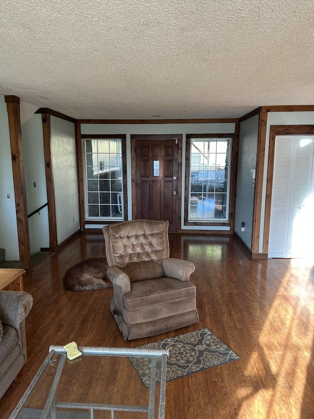 living room featuring wood-type flooring, crown molding, and a textured ceiling