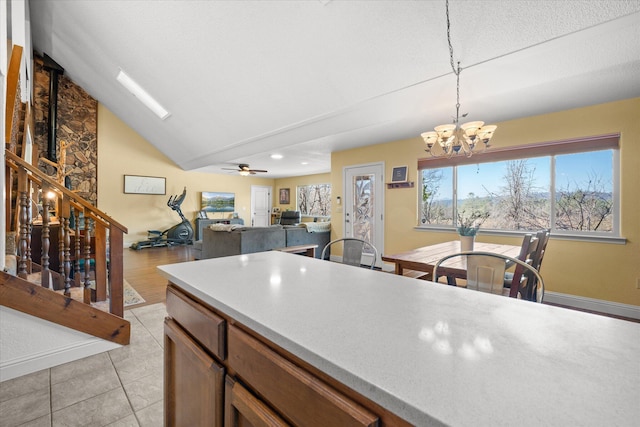 kitchen with ceiling fan with notable chandelier, lofted ceiling, light tile patterned floors, and decorative light fixtures