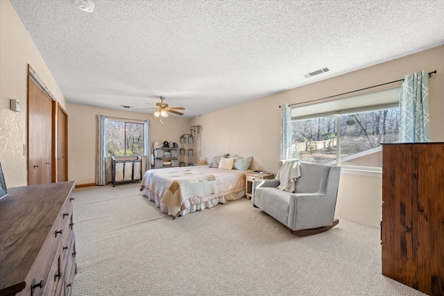 carpeted bedroom featuring ceiling fan and a textured ceiling