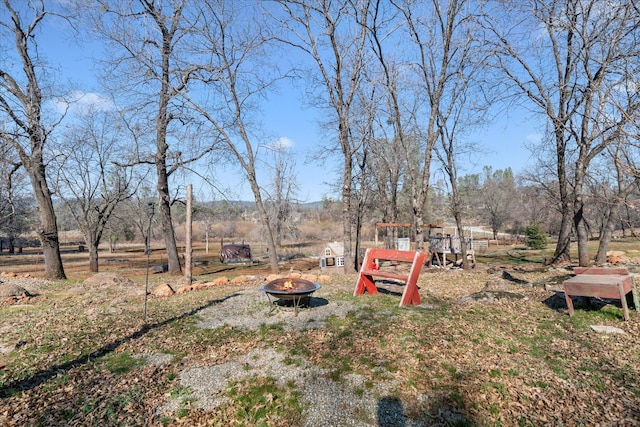 view of yard featuring a playground and an outdoor fire pit