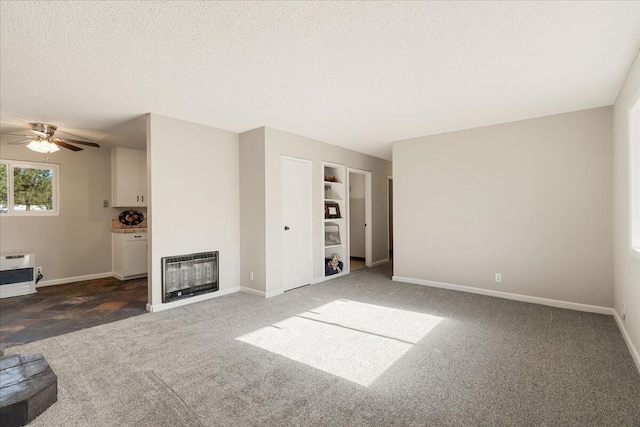 unfurnished living room featuring dark colored carpet, heating unit, and a textured ceiling