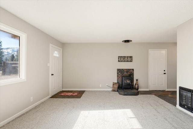 unfurnished living room featuring heating unit, a wood stove, and dark colored carpet