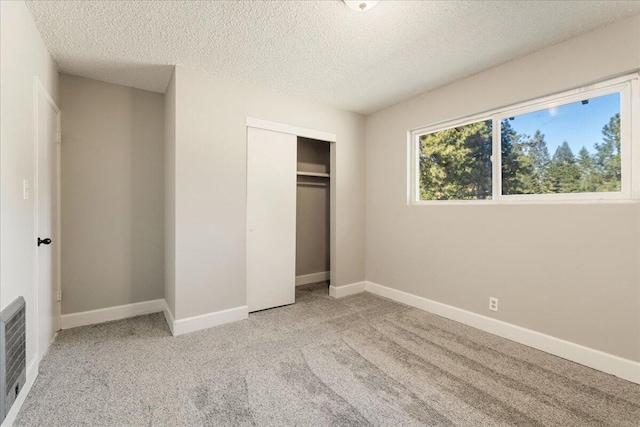 unfurnished bedroom featuring light carpet, a closet, and a textured ceiling