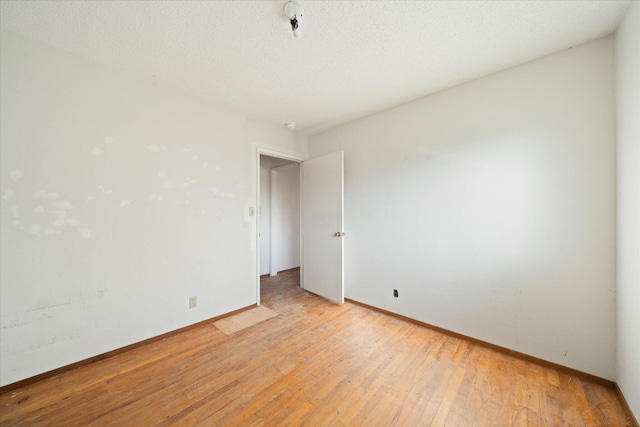 spare room featuring a textured ceiling and light wood-type flooring