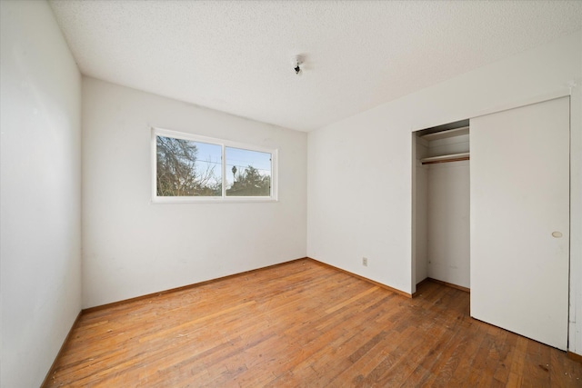 unfurnished bedroom with wood-type flooring, a closet, and a textured ceiling