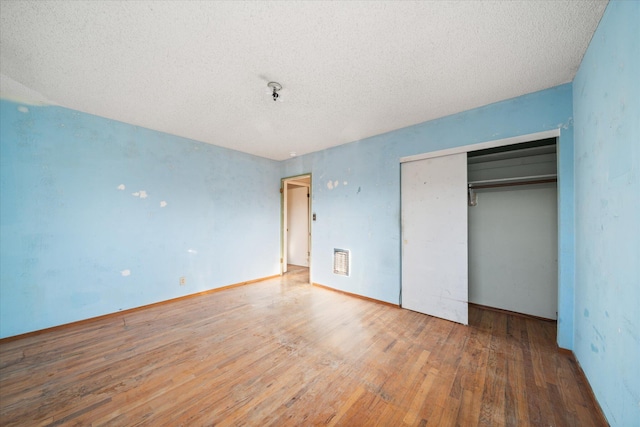 unfurnished bedroom featuring hardwood / wood-style flooring, a textured ceiling, and a closet