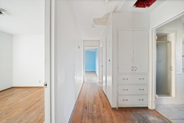 hall with hardwood / wood-style flooring and a textured ceiling