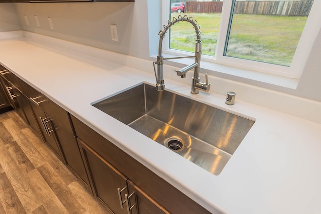 room details with dark brown cabinetry, sink, and light wood-type flooring