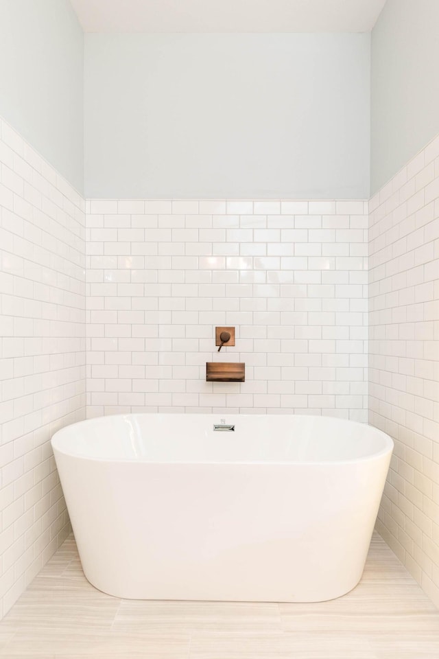 bathroom featuring tile walls and a tub to relax in