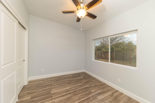 unfurnished bedroom with dark wood-type flooring, ceiling fan, and a closet