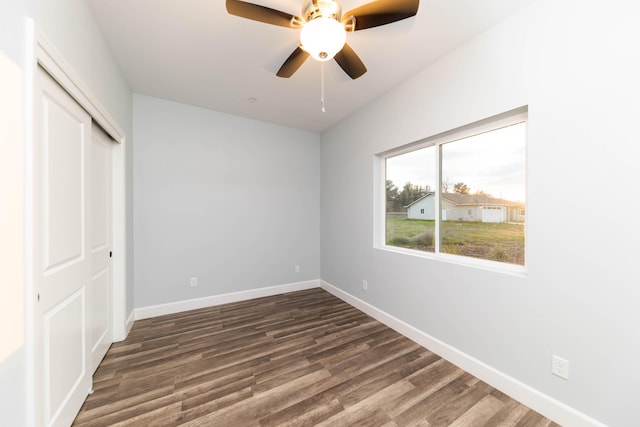 unfurnished bedroom featuring dark wood-type flooring, a closet, and ceiling fan