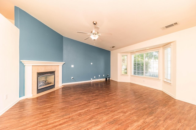 unfurnished living room featuring lofted ceiling, hardwood / wood-style floors, a tiled fireplace, and ceiling fan