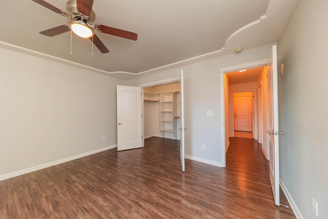 unfurnished bedroom featuring ceiling fan, dark hardwood / wood-style floors, and a spacious closet