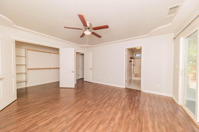 unfurnished bedroom featuring ensuite bathroom, hardwood / wood-style flooring, access to outside, ceiling fan, and a closet