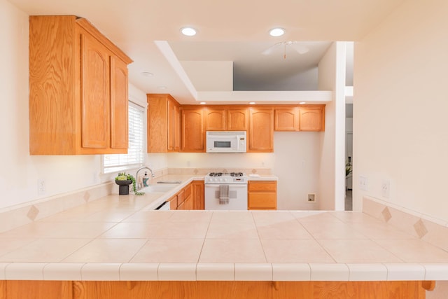 kitchen with recessed lighting, white appliances, a peninsula, and a sink