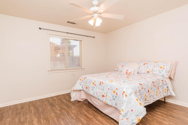 bedroom featuring visible vents, baseboards, wood finished floors, and a ceiling fan