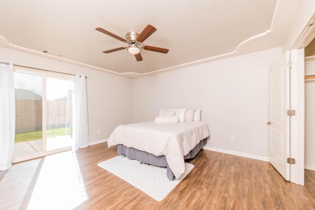 bedroom with access to exterior, visible vents, baseboards, and wood finished floors