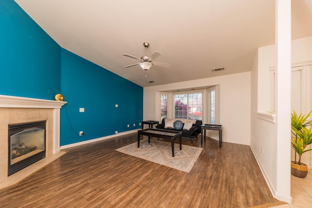 living area with visible vents, ceiling fan, baseboards, a fireplace with flush hearth, and wood finished floors