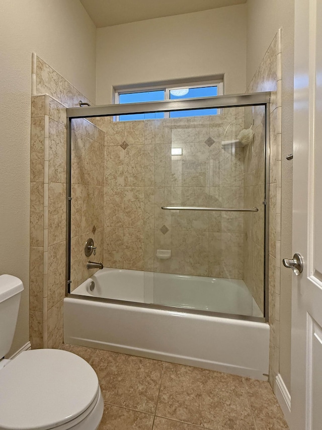 bathroom with bath / shower combo with glass door, tile patterned floors, and toilet