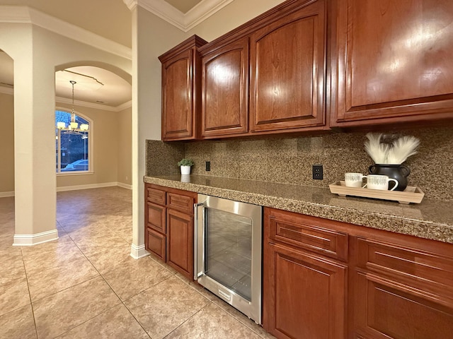 kitchen with light tile patterned floors, hanging light fixtures, wine cooler, tasteful backsplash, and ornamental molding