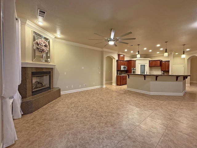 living room featuring light tile patterned flooring, ceiling fan, ornamental molding, and a fireplace