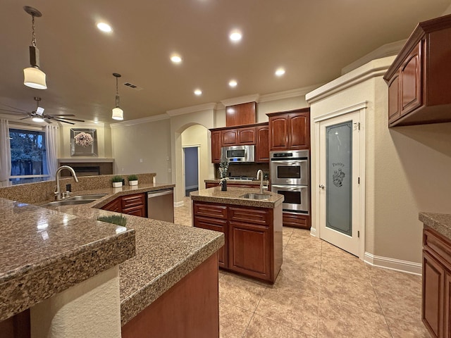 kitchen with pendant lighting, stainless steel appliances, sink, and a center island with sink