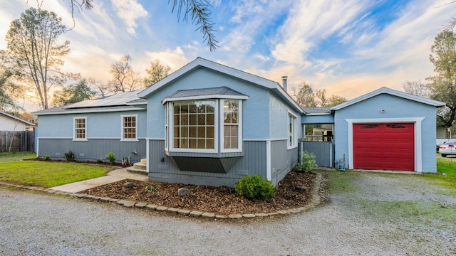 view of front of home featuring a yard, a garage, and solar panels