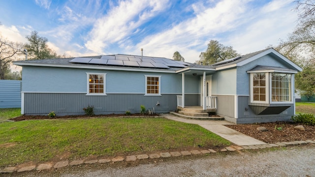 ranch-style home featuring a front lawn and solar panels