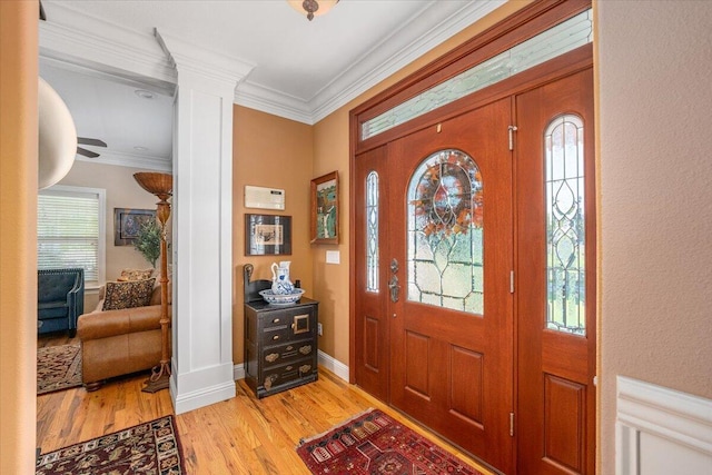 entryway with decorative columns, ornamental molding, and light hardwood / wood-style flooring