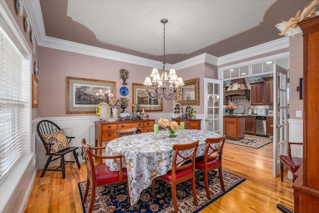 dining area featuring crown molding, an inviting chandelier, and light wood-type flooring