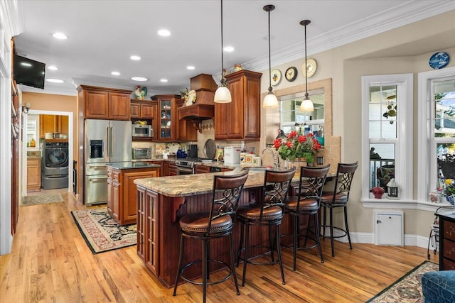 kitchen featuring premium range hood, decorative light fixtures, washer / clothes dryer, kitchen peninsula, and stainless steel appliances