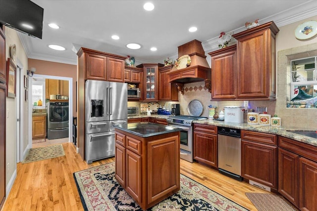 kitchen with crown molding, stainless steel appliances, a center island, and dark stone counters