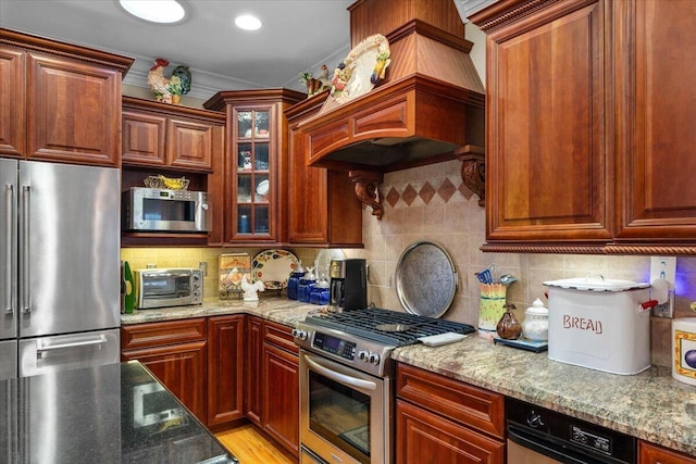 kitchen with tasteful backsplash, custom exhaust hood, light hardwood / wood-style floors, stainless steel appliances, and light stone countertops