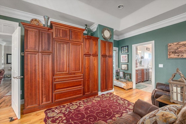 interior space with ornamental molding, connected bathroom, and light hardwood / wood-style floors