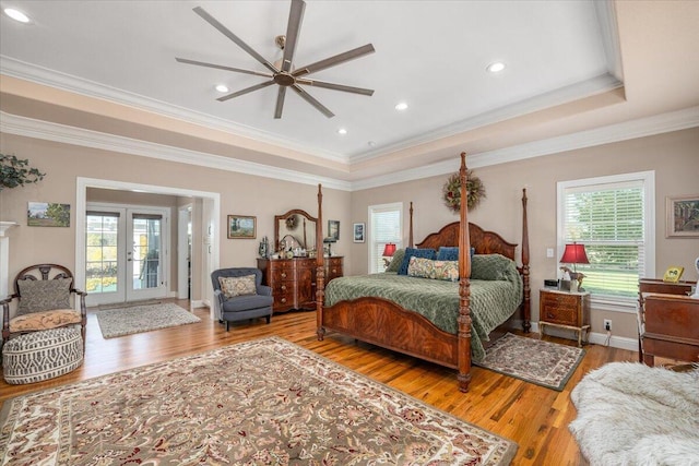 bedroom with wood-type flooring, ceiling fan, a raised ceiling, crown molding, and french doors