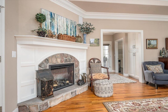 living area with crown molding, a fireplace, and light hardwood / wood-style floors