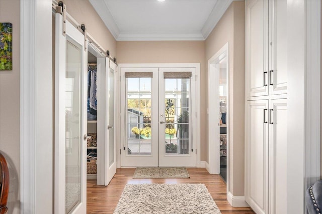 doorway to outside featuring crown molding, light hardwood / wood-style flooring, french doors, and a barn door