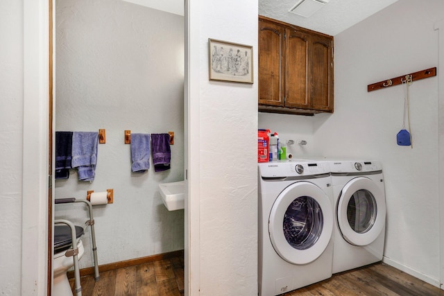 laundry area featuring dark wood-type flooring, washing machine and dryer, and cabinets